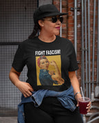 Person wearing a t-shirt with 'Fight Fascism!' graphic design outdoors.